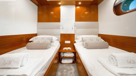 The two single beds in the double room are separated in the middle by a night console.